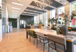 Moderne kantoorruimte aan de Barbara Strozzilaan met grote ramen, houten vloer en een lange vergadertafel.